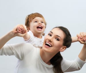 A happy mother holding her baby on her back and lifting up her hands