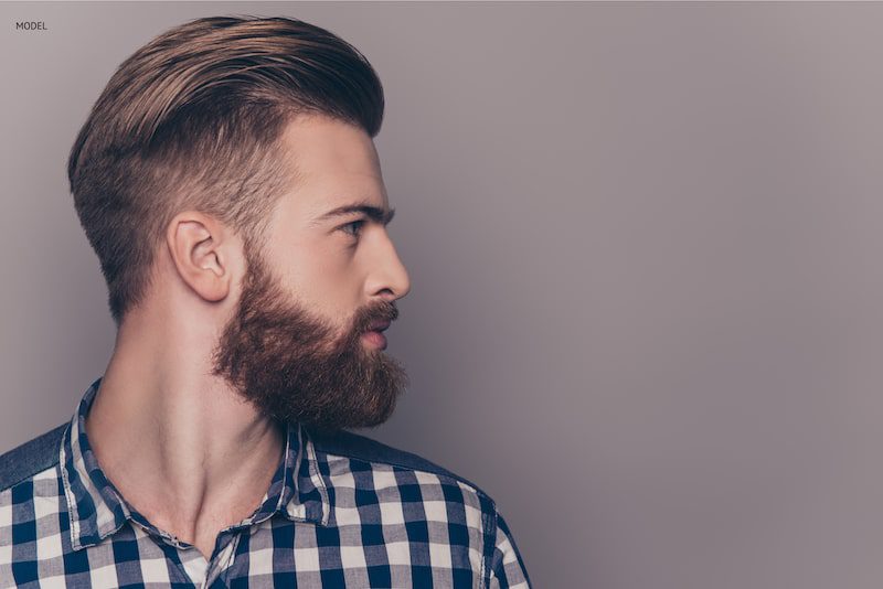 Man with a full beard looking to his left to show his profile.