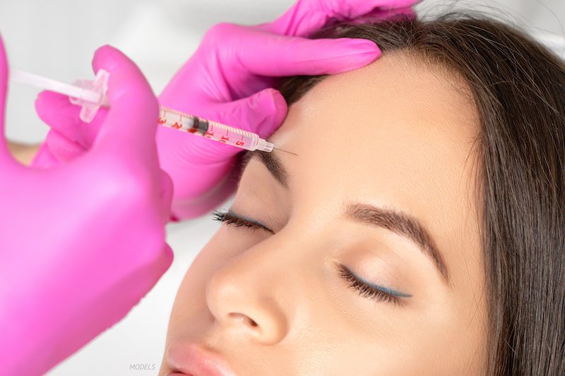 Young woman getting an injectable treatment in her forehead/brow area.