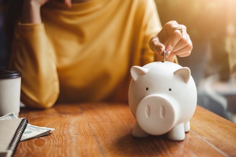 A woman puts money into a piggy bank.
