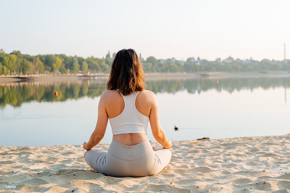 Woman meditating at a lake